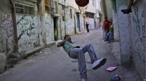 A Palestinian boy performs an overhead kick in an alley of Al-Amari refugee camp in the West Bank.